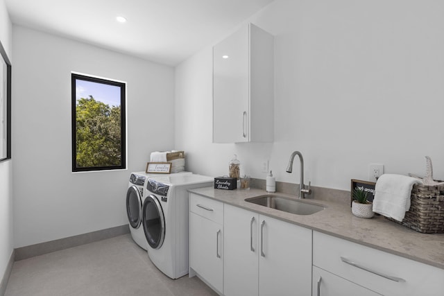 clothes washing area featuring cabinets, washing machine and clothes dryer, and sink