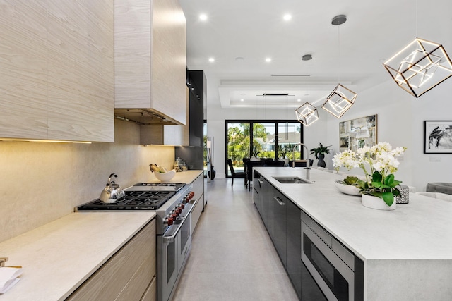 kitchen with decorative light fixtures, tasteful backsplash, sink, a large island with sink, and stainless steel appliances