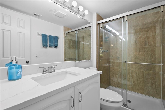 bathroom featuring a shower with door, vanity, and toilet