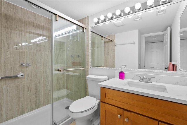 bathroom featuring toilet, vanity, and a shower with shower door