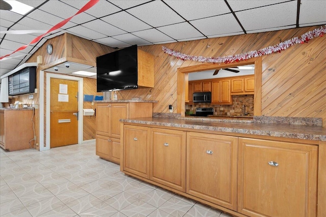 kitchen with wood walls, sink, backsplash, a drop ceiling, and electric stove