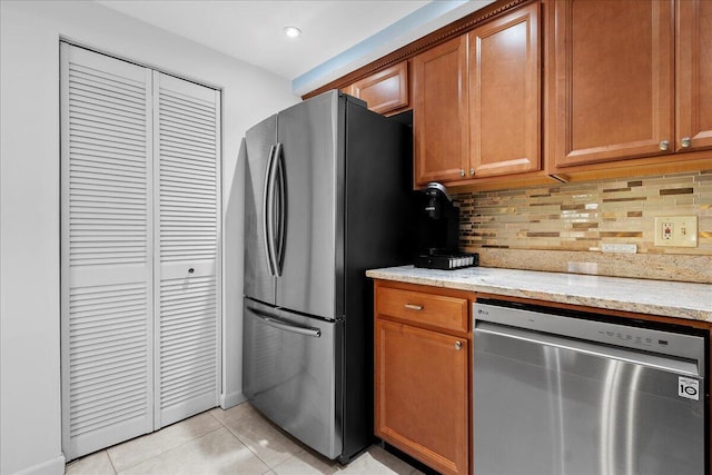 kitchen featuring stainless steel appliances, light tile patterned floors, backsplash, and light stone counters