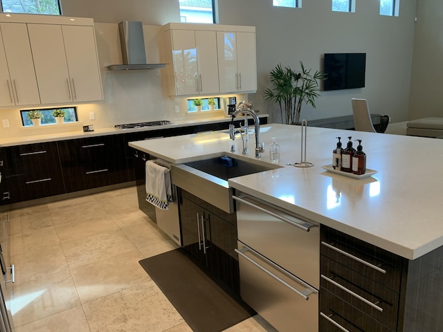 kitchen featuring white cabinetry, dark brown cabinets, sink, and wall chimney range hood