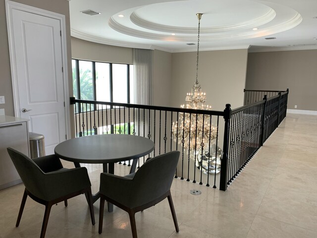 dining area with a raised ceiling, ornamental molding, and a notable chandelier