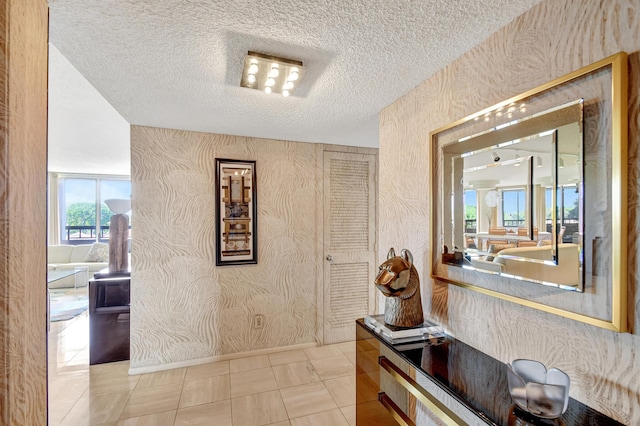 hallway featuring a textured ceiling and light tile patterned floors