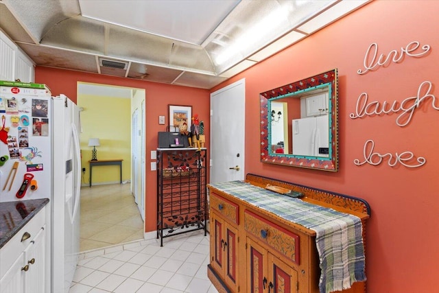 kitchen featuring white cabinets, light tile patterned floors, and white fridge with ice dispenser