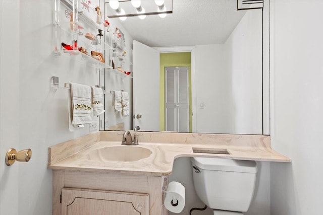 bathroom with vanity, toilet, and a textured ceiling