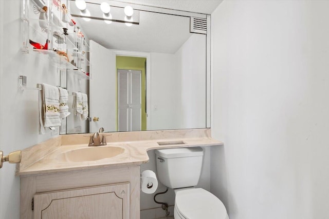 bathroom featuring vanity, a textured ceiling, and toilet