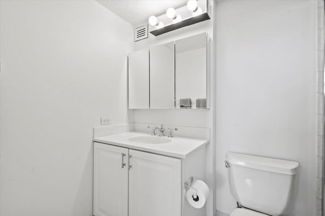 bathroom with vanity, toilet, and a textured ceiling