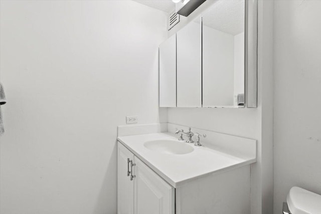 bathroom featuring vanity, a textured ceiling, and toilet