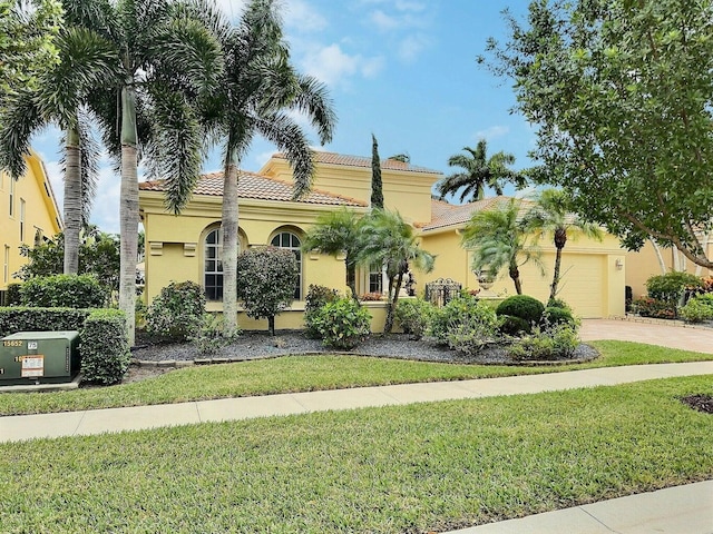 mediterranean / spanish house featuring a garage and a front lawn