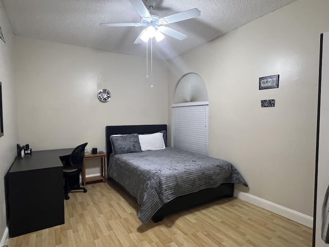 bedroom featuring ceiling fan, light hardwood / wood-style floors, and a textured ceiling