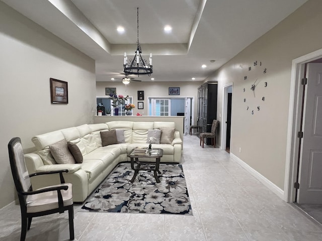 living room with light tile patterned flooring, ceiling fan, and a raised ceiling