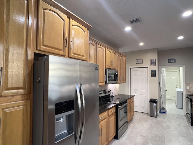 kitchen featuring stainless steel appliances, tasteful backsplash, and a textured ceiling