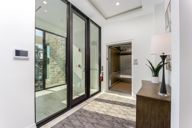 doorway with a wall of windows and a tray ceiling