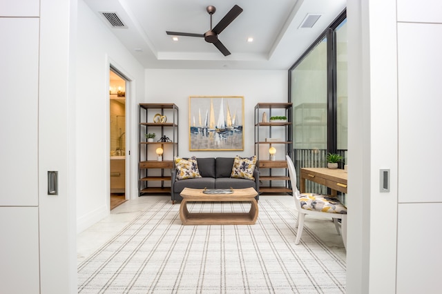 living area with a raised ceiling and ceiling fan