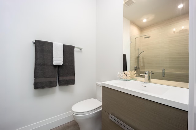 bathroom with vanity, a shower with door, and toilet