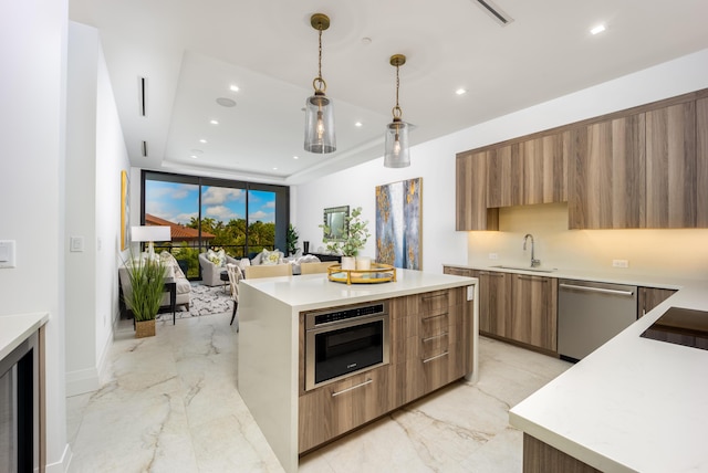 kitchen with appliances with stainless steel finishes, decorative light fixtures, sink, and a kitchen island