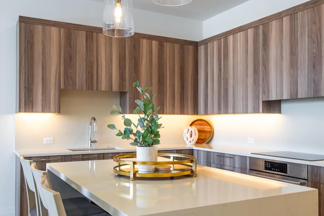 kitchen with black electric cooktop, sink, decorative light fixtures, and oven