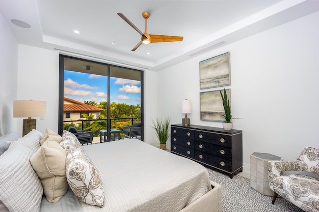 carpeted bedroom featuring ceiling fan, a wall of windows, access to exterior, and a raised ceiling