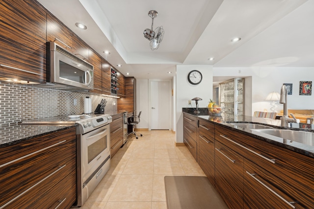 kitchen featuring sink, light tile patterned floors, stainless steel appliances, decorative backsplash, and dark stone counters