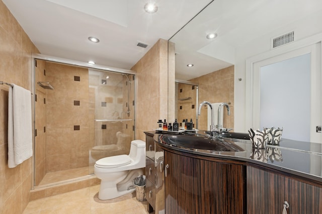 bathroom with tile patterned floors, toilet, a shower with shower door, tile walls, and vanity