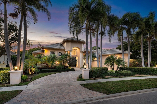 mediterranean / spanish home with decorative driveway, a tile roof, and stucco siding