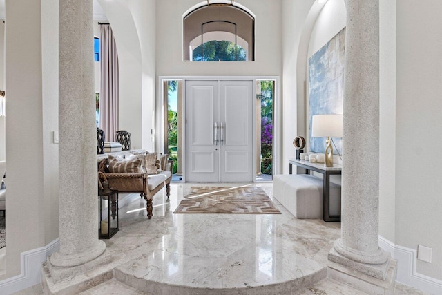 entrance foyer with marble finish floor, a healthy amount of sunlight, and decorative columns