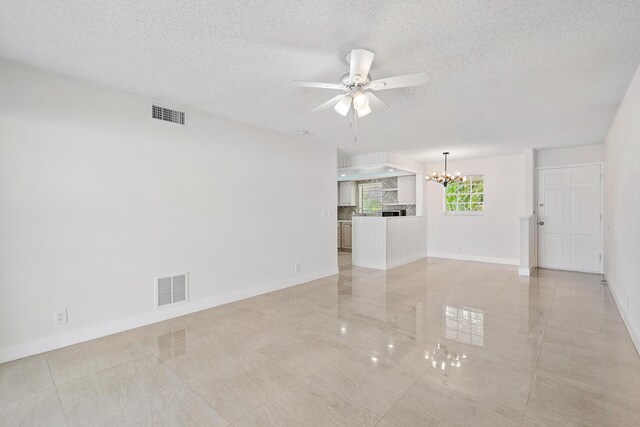 148 Yacht Club Dr Unit 12, North Palm Beach, FL 33408 - unfurnished living room featuring a chandelier, a ceiling fan, a textured ceiling, and light tile patterned flooring