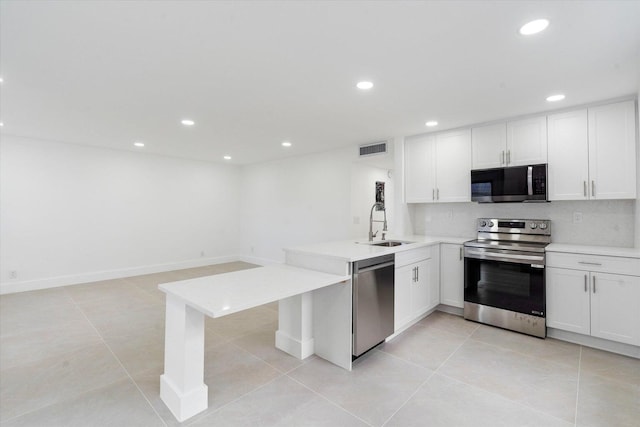 kitchen featuring appliances with stainless steel finishes, sink, white cabinets, decorative backsplash, and kitchen peninsula