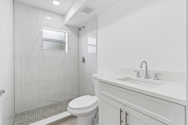 bathroom featuring vanity, toilet, and a tile shower