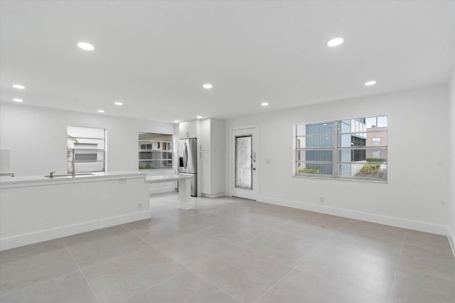 unfurnished living room featuring light tile patterned flooring and sink