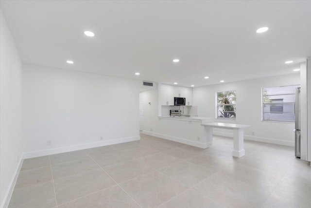 unfurnished living room featuring sink and light tile patterned flooring