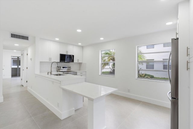 kitchen with sink, a breakfast bar, appliances with stainless steel finishes, white cabinetry, and kitchen peninsula