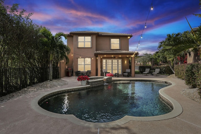 pool at dusk featuring french doors, an in ground hot tub, ceiling fan, and a patio