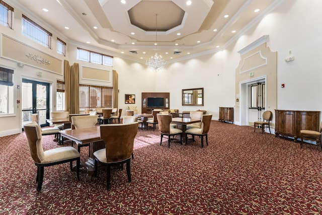 carpeted dining room featuring crown molding, a towering ceiling, a raised ceiling, and an inviting chandelier