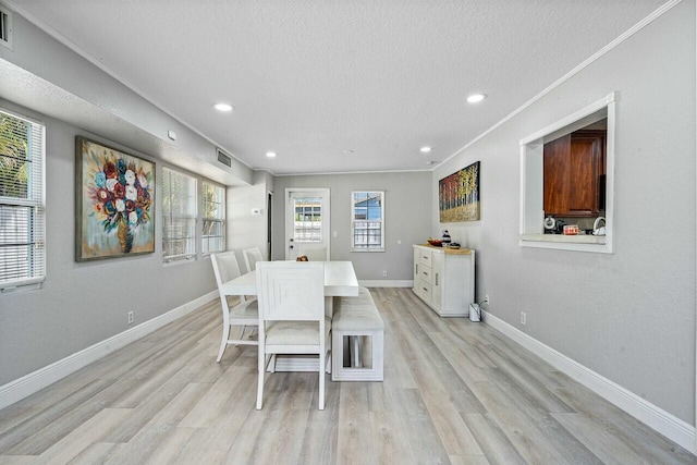 dining room featuring crown molding, a textured ceiling, and light hardwood / wood-style flooring