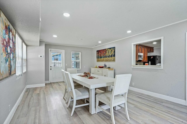 dining room featuring ornamental molding, light hardwood / wood-style floors, and a textured ceiling