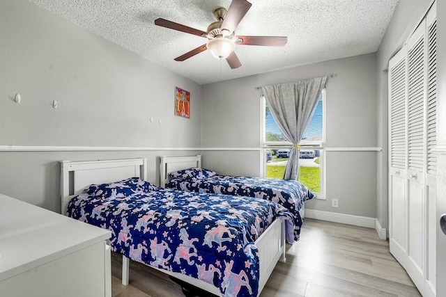 bedroom featuring ceiling fan, a closet, a textured ceiling, and light wood-type flooring