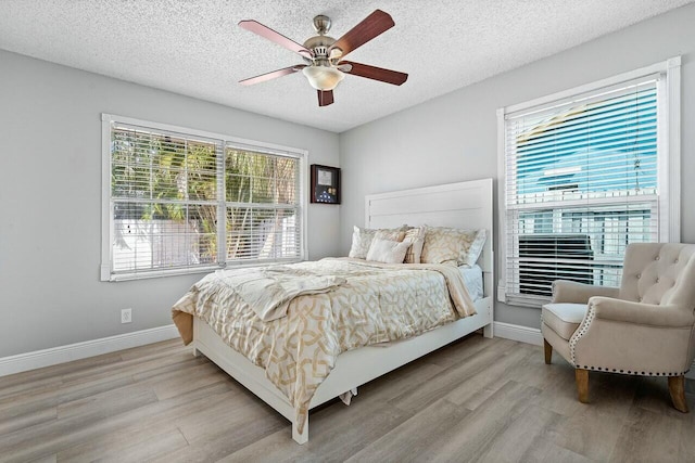 bedroom featuring ceiling fan, light hardwood / wood-style flooring, and a textured ceiling