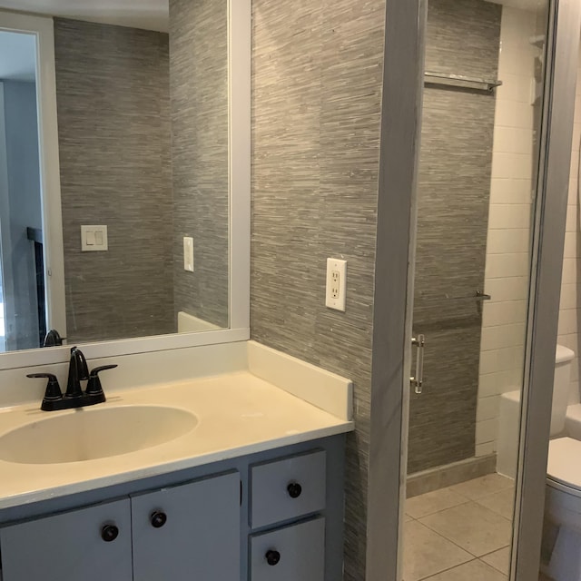 bathroom featuring tile patterned floors, toilet, tile walls, vanity, and a shower with door