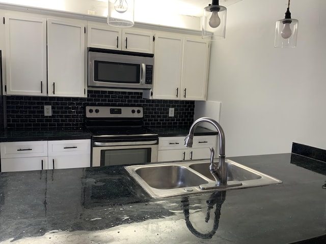 kitchen with appliances with stainless steel finishes, sink, white cabinets, decorative backsplash, and hanging light fixtures