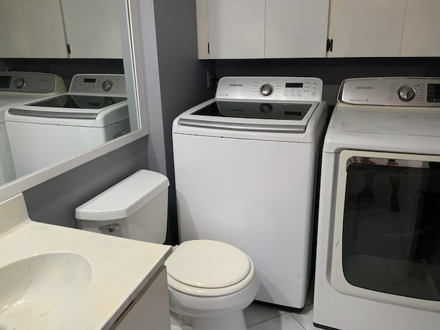 laundry area featuring washer and clothes dryer, sink, and light tile patterned floors