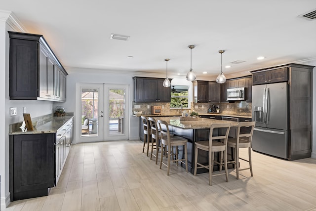 kitchen featuring pendant lighting, stone counters, stainless steel appliances, dark brown cabinetry, and a kitchen island