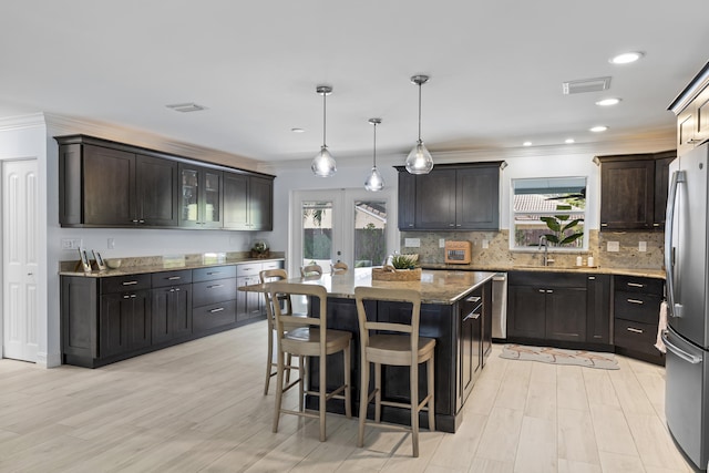 kitchen with a breakfast bar, dark brown cabinets, stainless steel appliances, a kitchen island, and decorative light fixtures