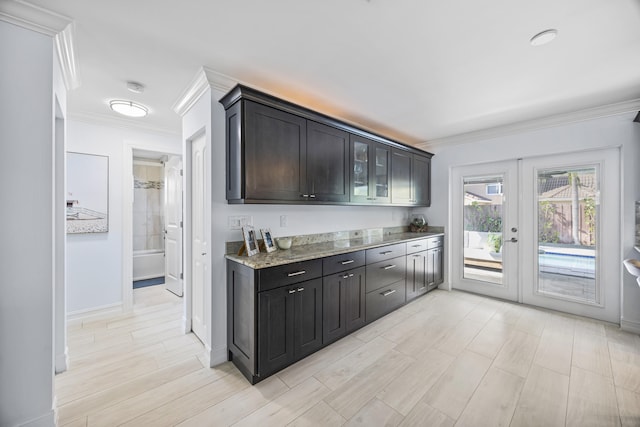 kitchen with light stone counters, ornamental molding, and french doors