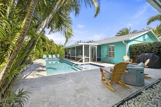 view of swimming pool with grilling area, a sunroom, and a patio