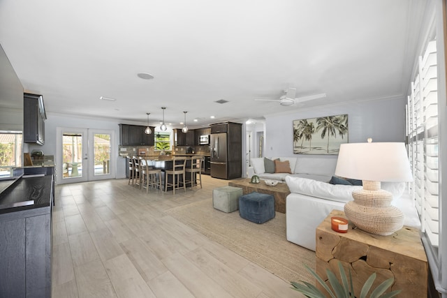 living room featuring ornamental molding, light hardwood / wood-style flooring, ceiling fan, and french doors