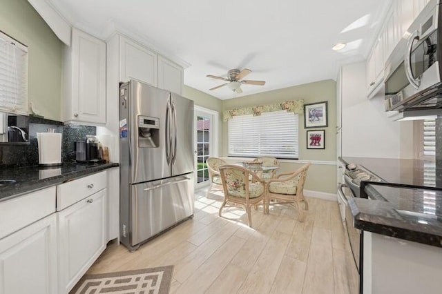 kitchen featuring appliances with stainless steel finishes, white cabinetry, dark stone countertops, decorative backsplash, and light wood-type flooring