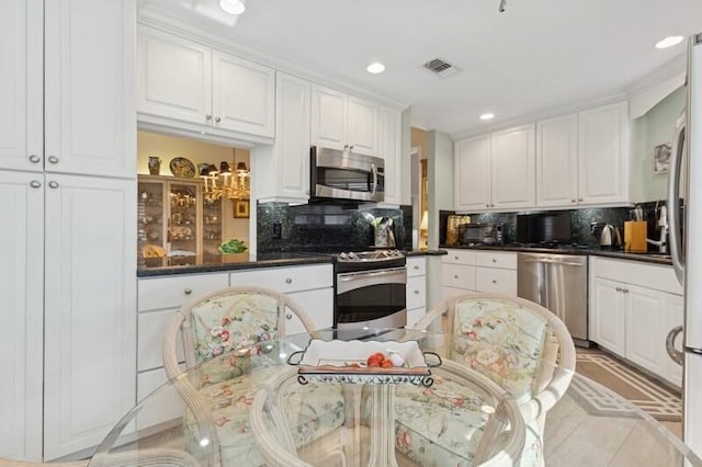 kitchen with stainless steel appliances, white cabinetry, and tasteful backsplash